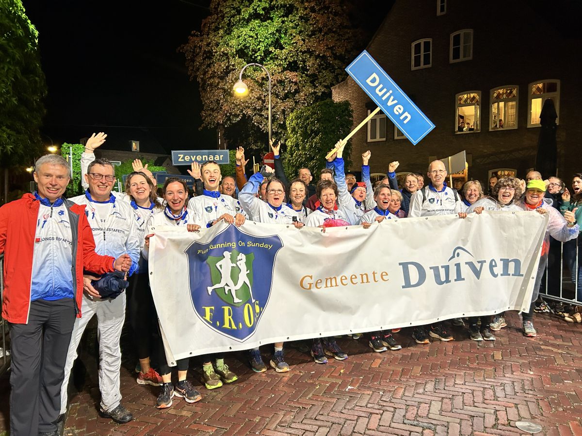 Groep deelnemers aan de bevreidingsestaffete met spandoek en vlag